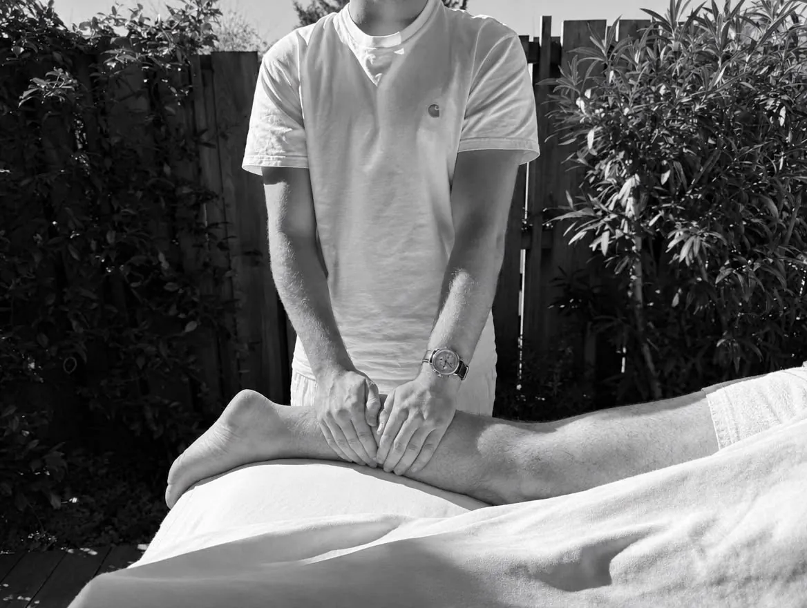 Hector draine le mollet d’un sportif, des mains vers le genou – Tarifs du massage sportif à Gujan-Mestras
