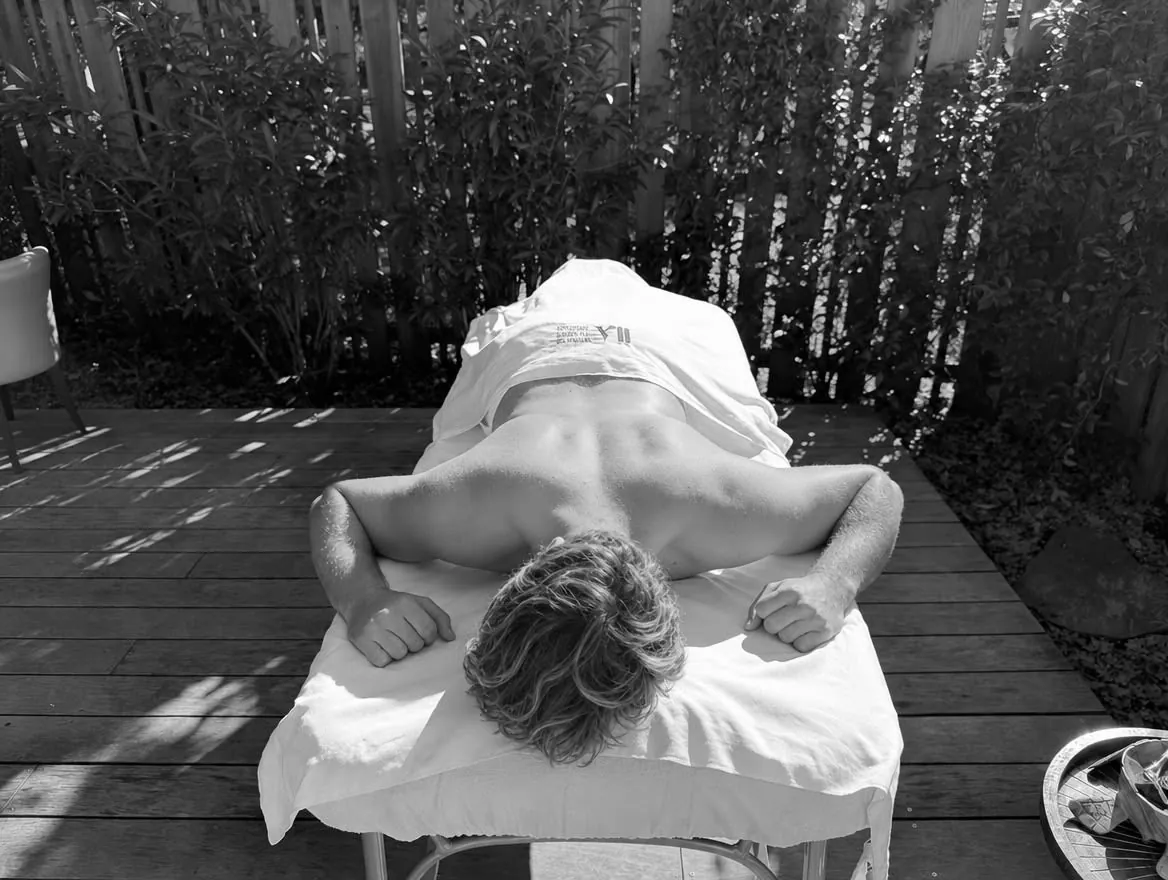 Sportif allongé sur la table de massage, sur la terrasse de l’institut – Massage sportif et récupération à Gujan-Mestras, Bassin d’Arcachon